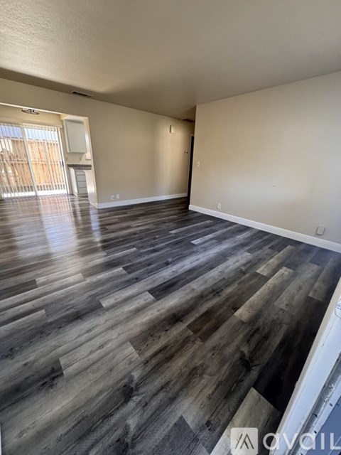 A spacious room with wooden flooring and white walls.