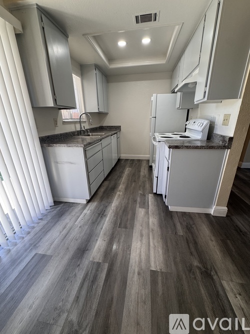 A kitchen with white appliances and wooden floors.