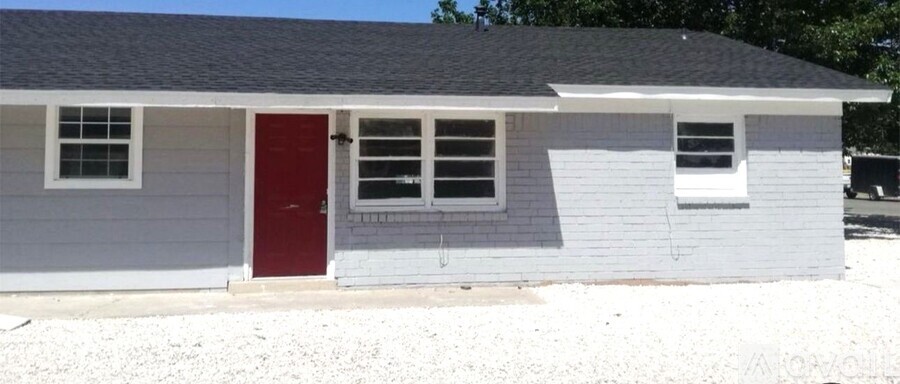 A small house with a red door and a grey siding.