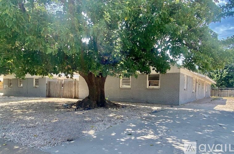 A tree in front of a building with the word "available" written on it.