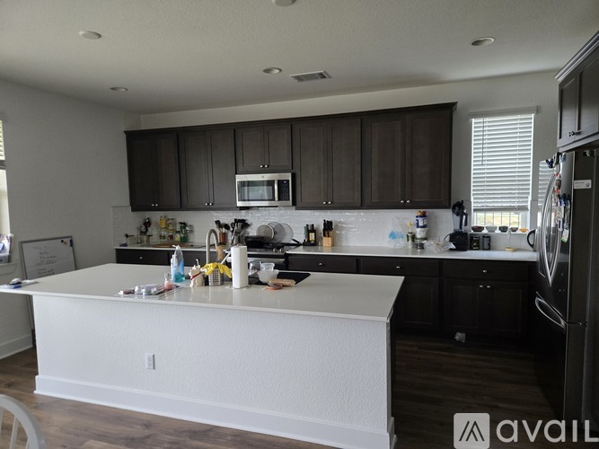 A kitchen with white countertops and dark brown cabinets.