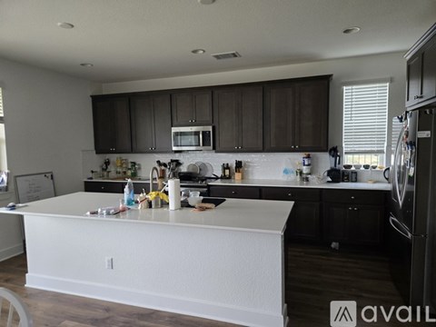 A kitchen with white countertops and dark brown cabinets.