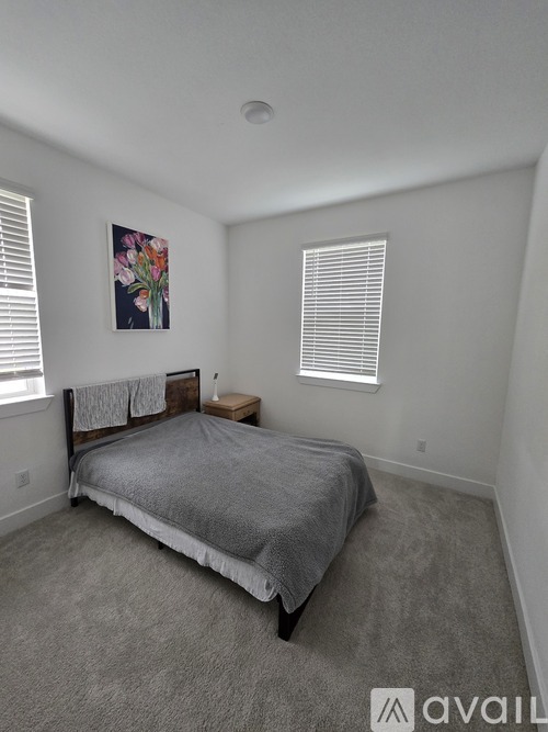 A bedroom with a bed, carpet, and a painting on the wall.