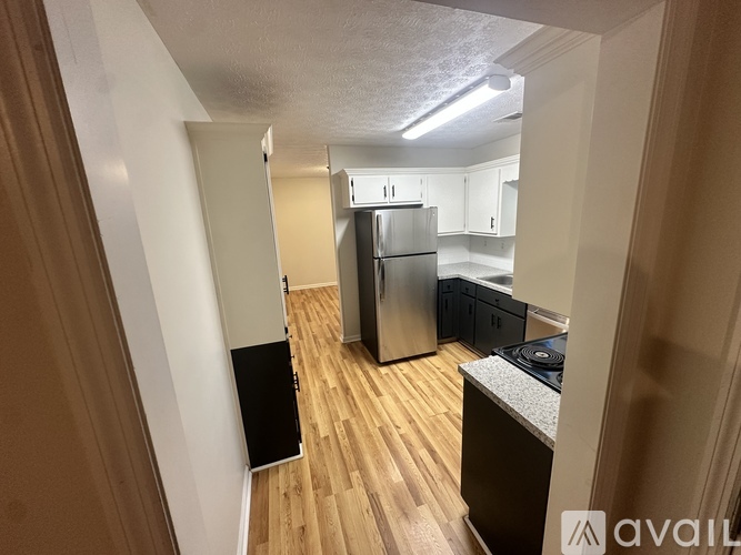 A kitchen with a refrigerator, cabinets, and a stove top oven.