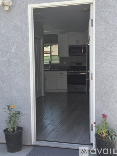 A doorway opens to a kitchen with a wooden floor.