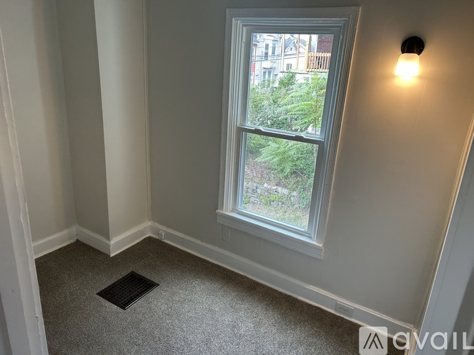 A window in a room with a view of a building and trees outside.