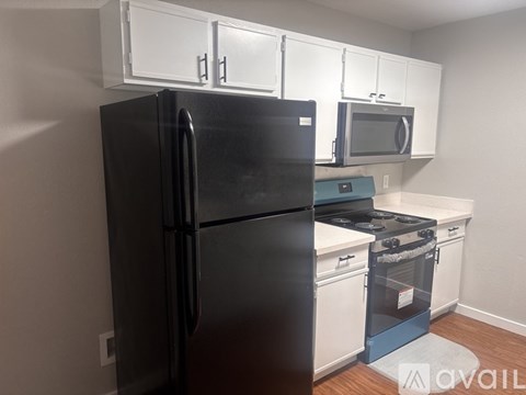 A black refrigerator and stove in a kitchen with white cabinets.