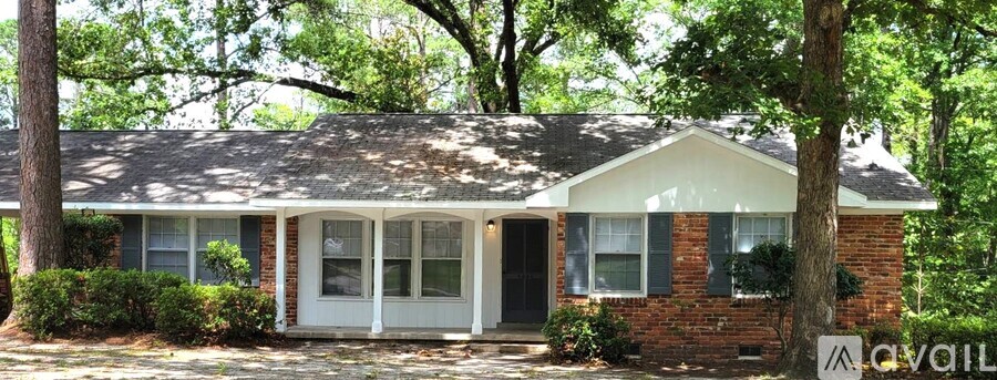 A house with a white door and windows is surrounded by trees.