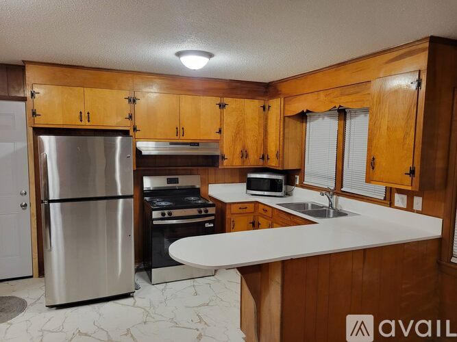 A kitchen with wooden cabinets and a stainless steel refrigerator.
