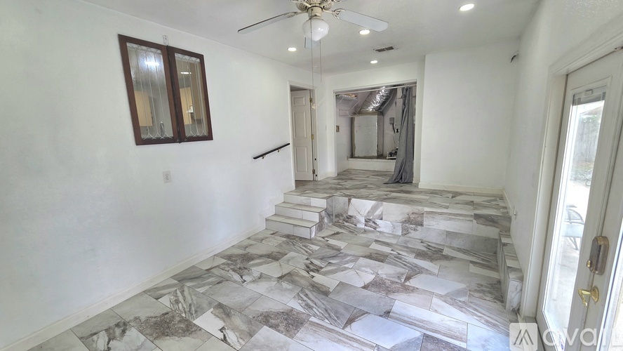 A spacious room with a marble floor and a ceiling fan.