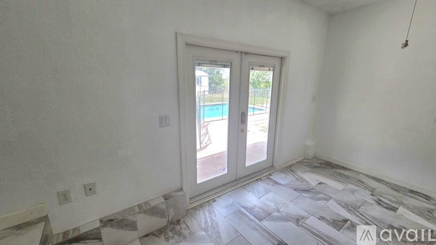 A room with a marble floor and a sliding glass door leading to a pool.
