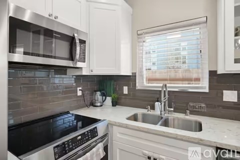A modern kitchen with a stainless steel oven and white cabinets.