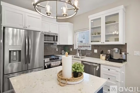 A kitchen with a white countertop and a basket of greenery on it.