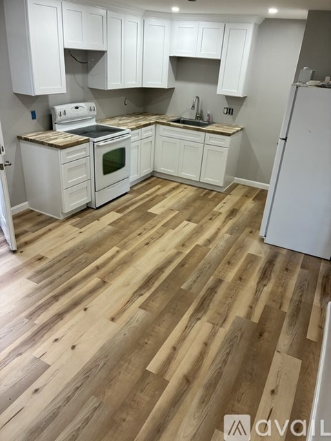 A kitchen with white cabinets and a wooden floor.