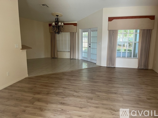 A spacious living room with hardwood floors and a chandelier.