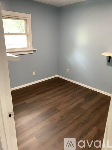 A room with wooden flooring and a window.