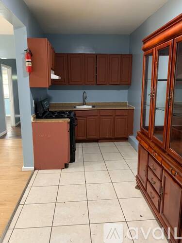 A kitchen with brown cabinets and a red appliance.