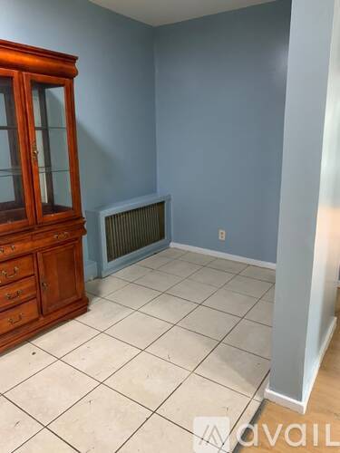 A room with a wooden cabinet and a wall-mounted heater.