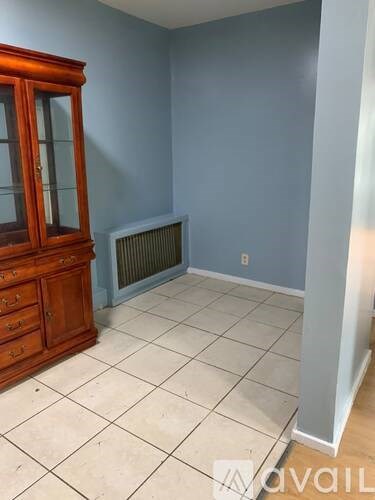 A room with a wooden cabinet and a wall-mounted heater.