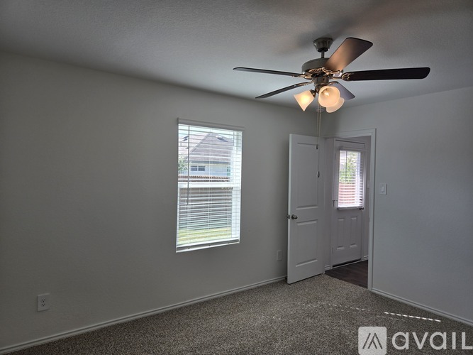 A room with a ceiling fan and a window with blinds.