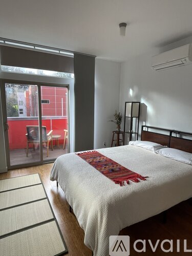 A bedroom with a large bed and a sliding glass door leading to a balcony.