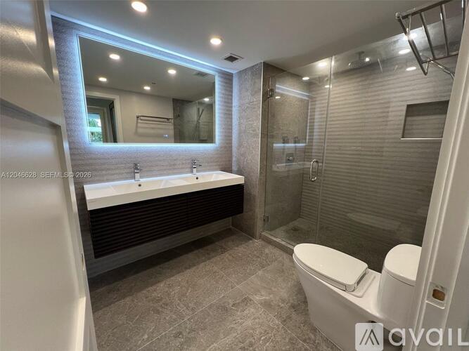 A modern bathroom with a large mirror and a glass shower stall.
