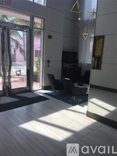 A room with a glass door leading outside, a black chair, and a mirror on the wall.