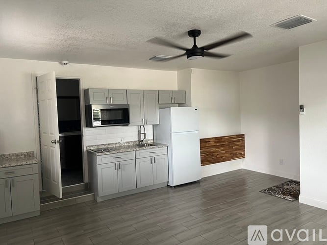 A kitchen with a refrigerator, sink, and cabinets.