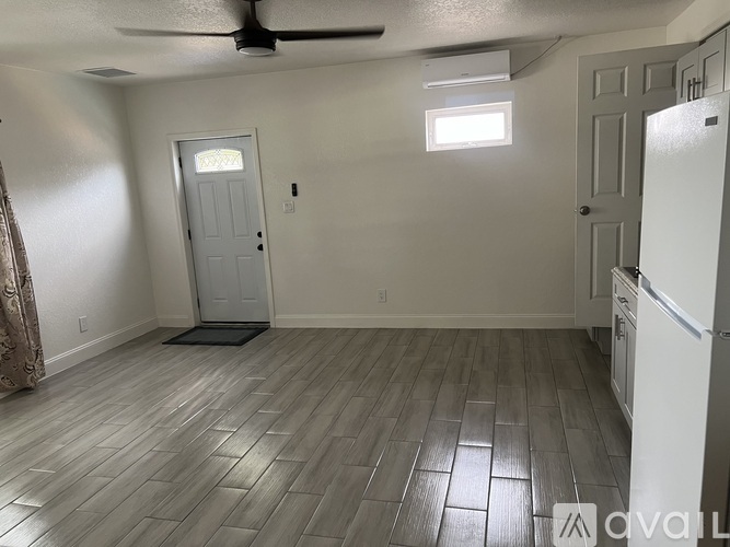 A kitchen area with a refrigerator, a door, and a window.