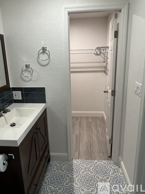 A bathroom with a sink and a doorway leading to a bedroom.