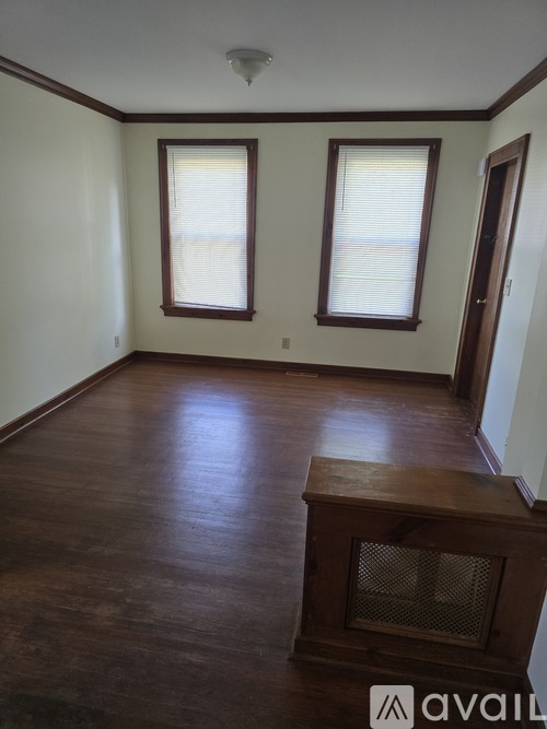 A room with wood floors and two windows.