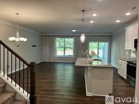 A spacious kitchen and living room with a staircase leading to the upper floor.