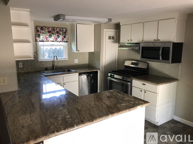 A kitchen with granite countertops and white cabinets.