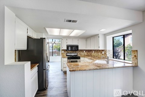 A kitchen with white cabinets and a granite countertop.