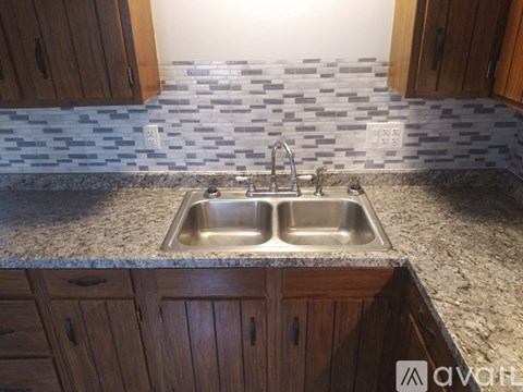 A kitchen with a sink and wooden cabinets.