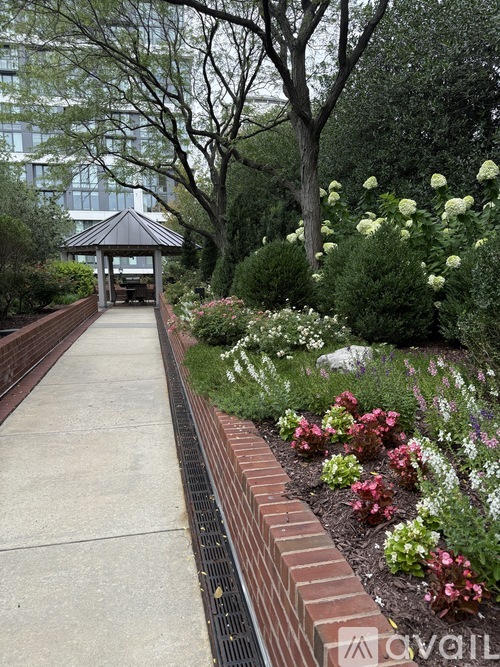 A garden with a brick border and a gazebo in the background.