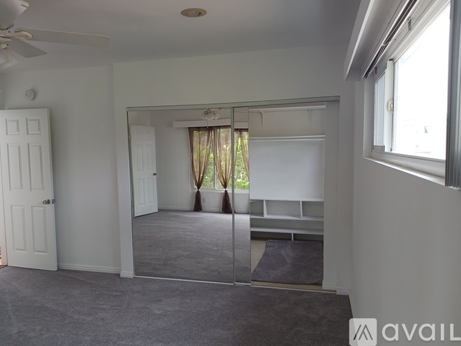 A spacious room with a large mirror and a ceiling fan.