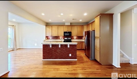 A kitchen with wooden cabinets and a brick backsplash is available for rent.