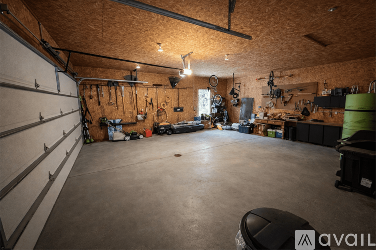 A spacious garage with a variety of tools hanging on the walls and a concrete floor.