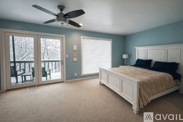 A bedroom with a bed, a ceiling fan, and a sliding glass door.