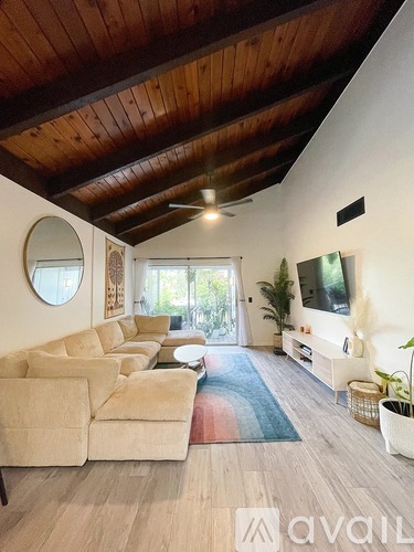 A living room with a white couch and a round mirror on the wall.