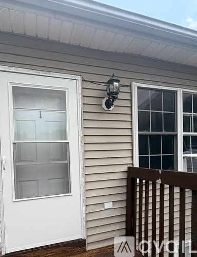 A white door with a window above it and a lantern on the wall.