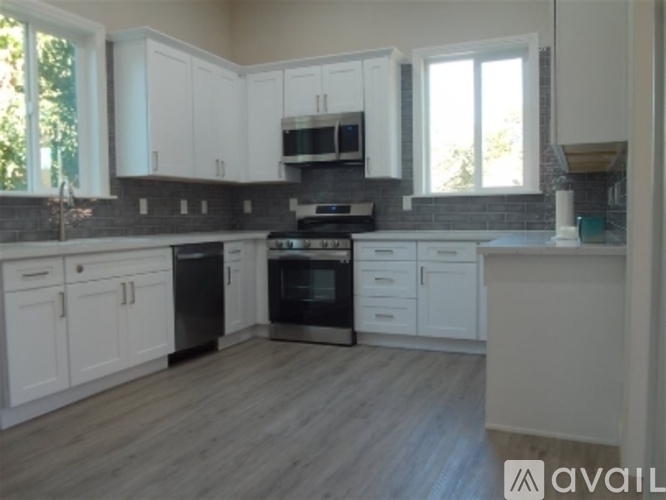 A kitchen with white cabinets and a wooden floor.