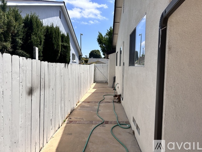 A long concrete walkway with a green hose on it.
