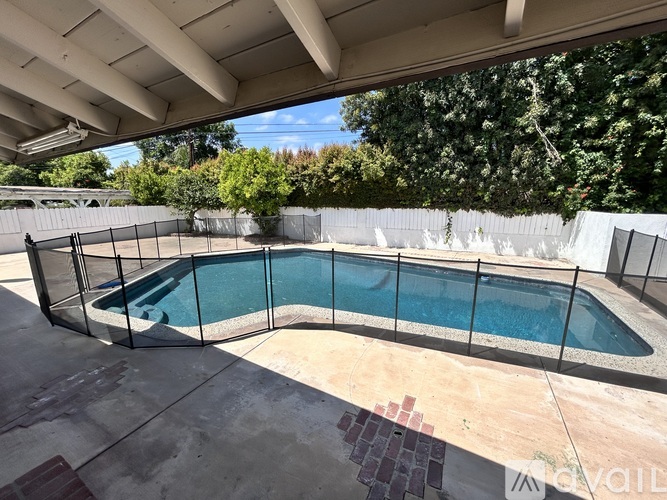 A pool surrounded by a black fence under a roof.