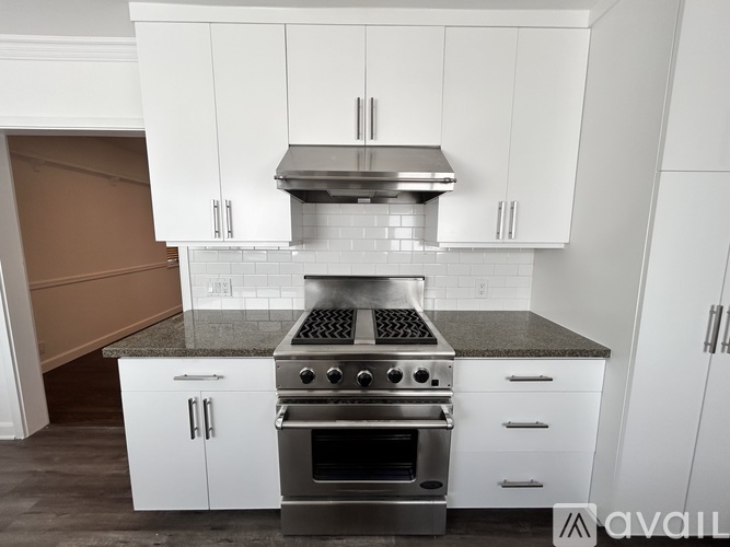 A modern kitchen with white cabinets and a stainless steel range hood.