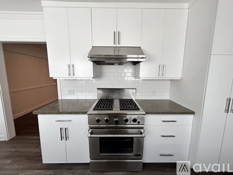 A modern kitchen with white cabinets and a stainless steel range hood.