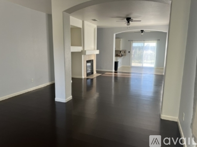 A spacious living room with a dark floor and white walls.