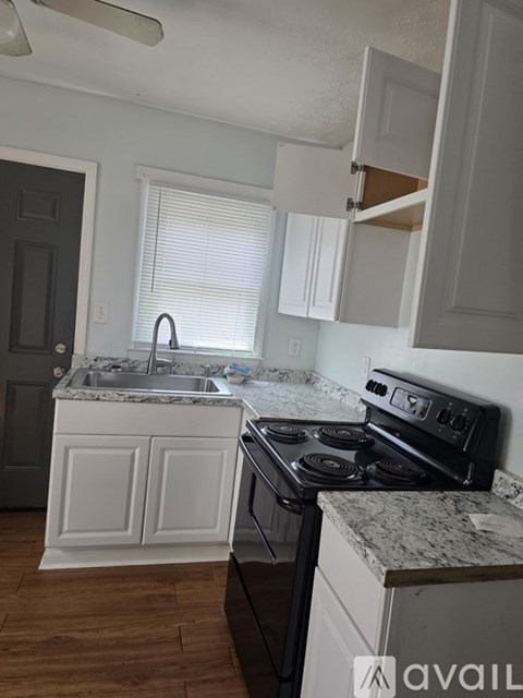 A kitchen with a black stove top oven and a marble counter top.