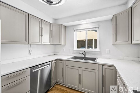 A kitchen with a stainless steel dishwasher and white countertops.